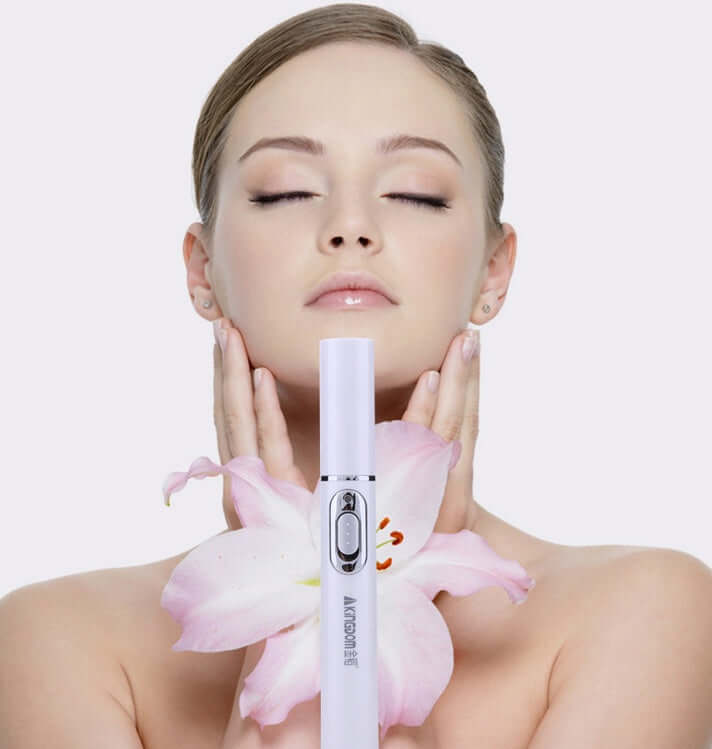 Model using blue light therapy acne laser pen with floral accents for skincare and beauty routine.
